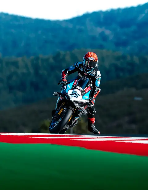 Motorradfahrer auf einem schwarzen Rennmotorrad über einer Kuppe