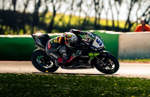 Schwarzes Rennmotorrad in Schräglage vor sonniger Strecke